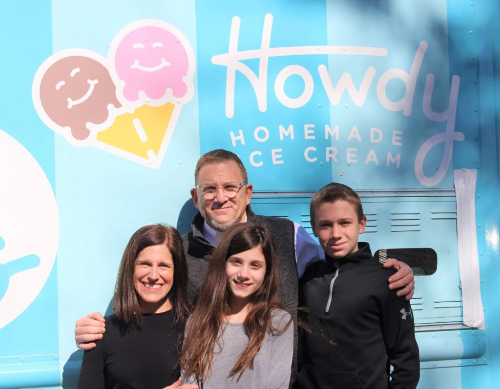 family standing in front of howdy homemade sign